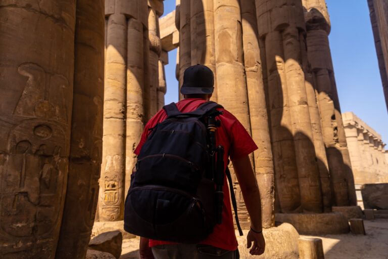 A photographer looking at ancient Egyptian drawings on the columns of the Temple of Luxor, Egypt