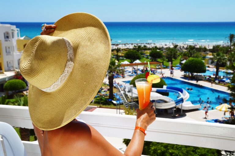 Woman with drink on the balcony in a tourist resort.